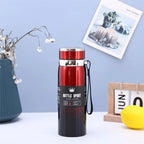 Red and black insulated bottle on a table with decorative items in the background