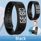 Black digital fitness tracker with charging cable on a blue background