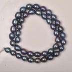 A strand of irregular baroque freshwater pearls arranged in a loop on a plain light background. The pearls have a deep blue-green iridescent sheen with subtle purplish undertones.