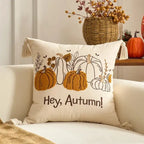 Decorative pillow with pumpkins and 'Hey, Autumn!' text on a couch.