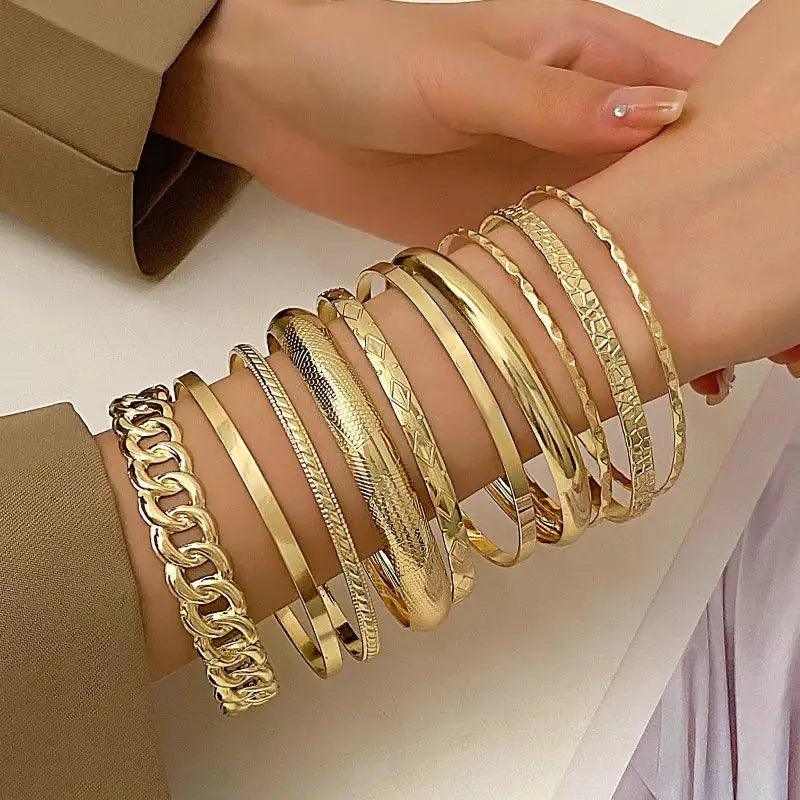 Gold bracelets on a wrist with a neutral background