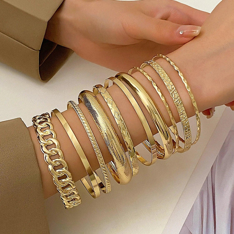 Gold bracelets on a wrist with a neutral background