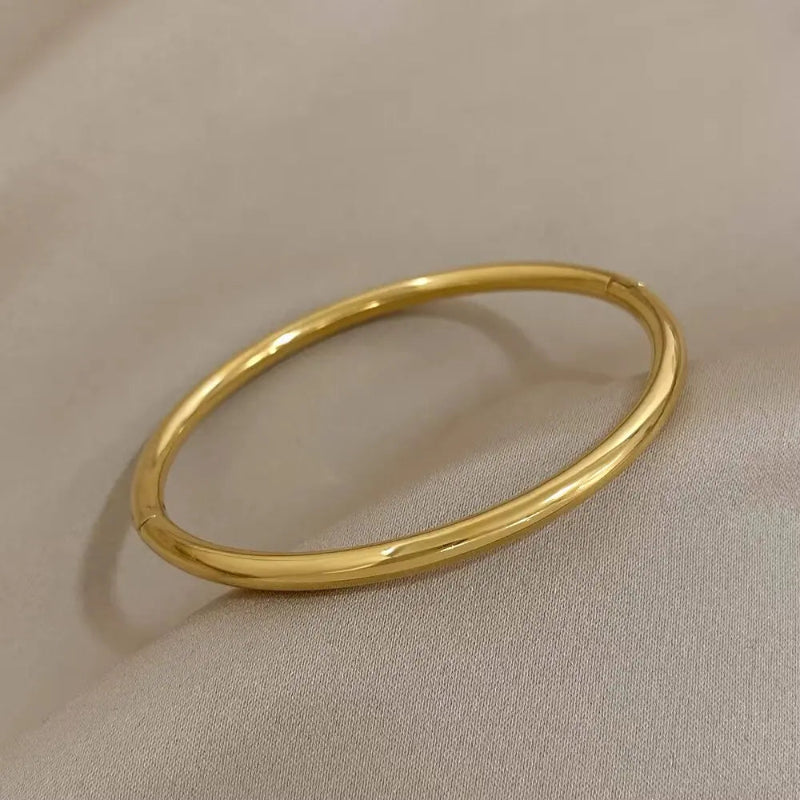 Gold bangle on a beige fabric background