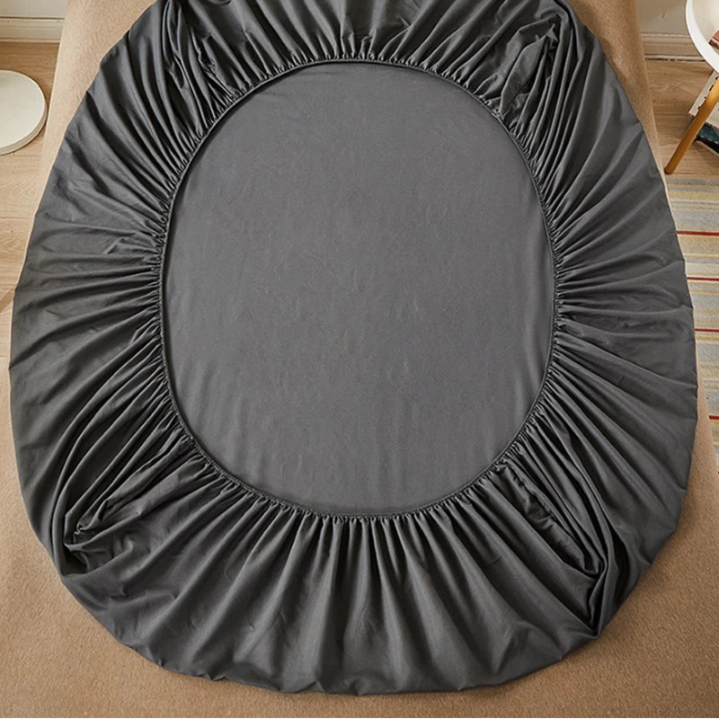 Gray fitted sheet on a bed in a room with 'vave' branding.