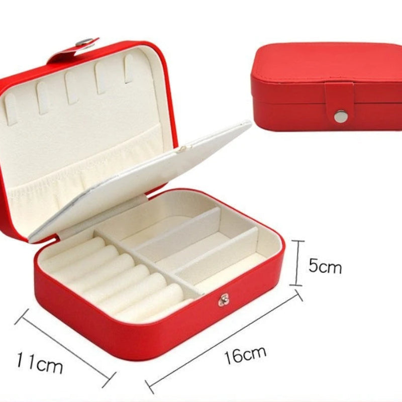 Red jewelry box shown open and closed on a white background, with dimension labels indicating 11 cm width, 16 cm length, and 5 cm height. The box has a red exterior, white interior compartments, and a small silver snap closure.