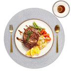 Steak dish with vegetables on a white plate with gold cutlery on a gray placemat.