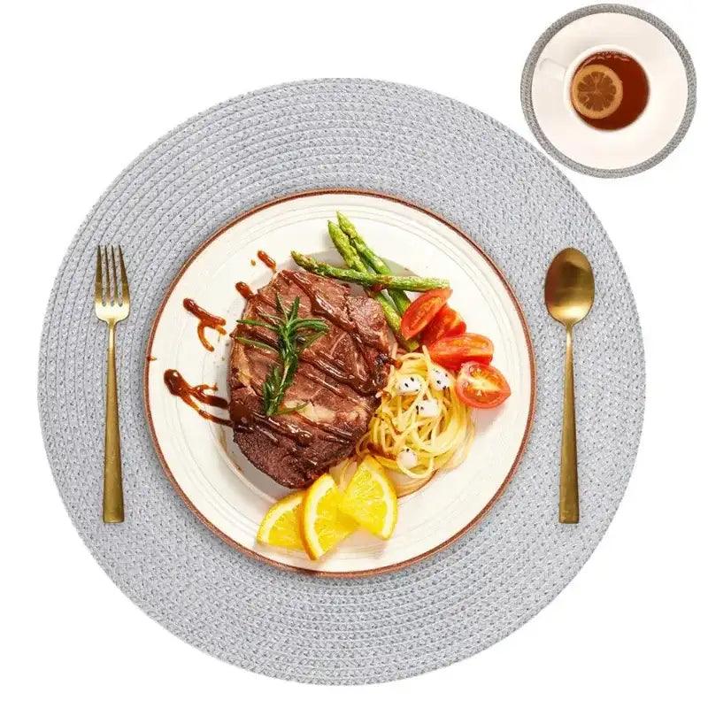 Steak dish with vegetables on a white plate with gold cutlery on a gray placemat.