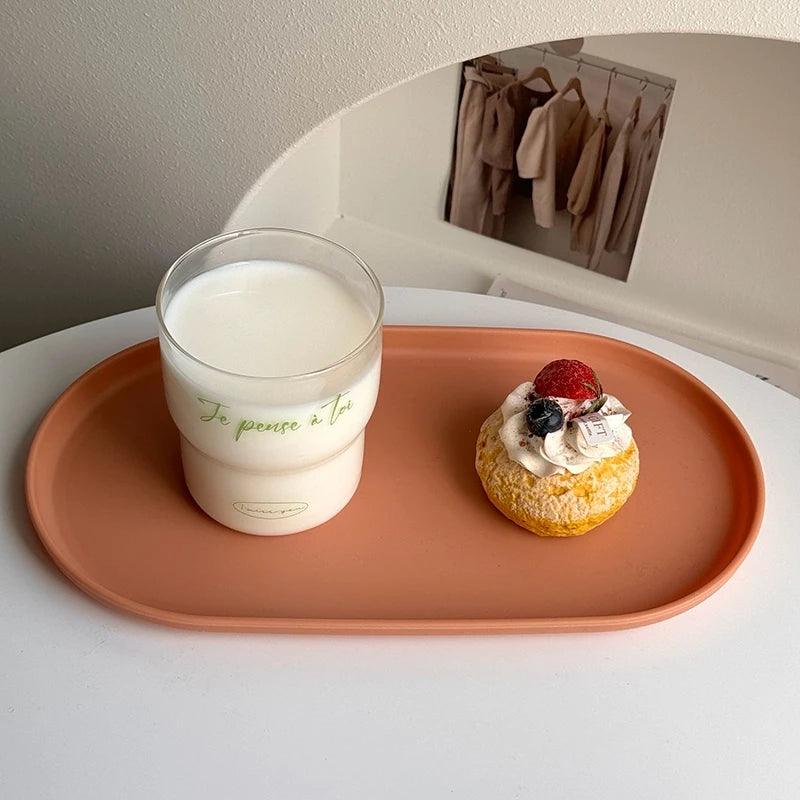 Cup of coffee and dessert on a pink tray with a mirror in the background