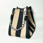 Black and beige striped handbag with a braided handle on a white background