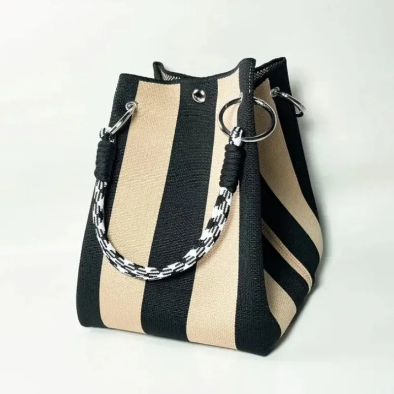 Black and beige striped handbag with a braided handle on a white background