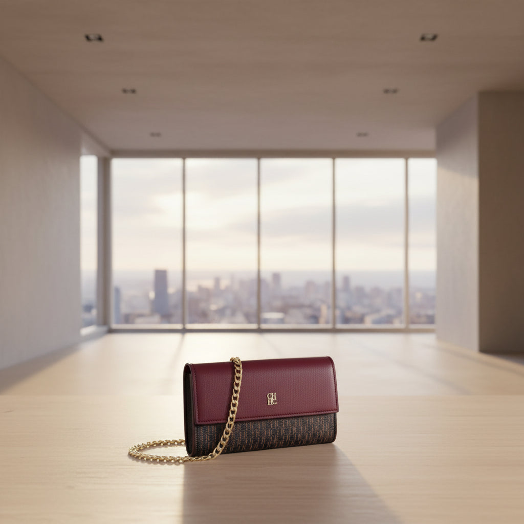 Burgundy handbag with gold chain strap on a white background