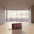 Burgundy handbag with gold chain strap on a white background