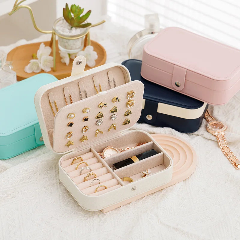 Jewelry organizer with rings, earrings, and a pink case on a white surface.