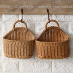 Two wicker baskets hanging on a textured white wall with French text above.