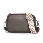 Gray crossbody bag with a patterned strap on a white background