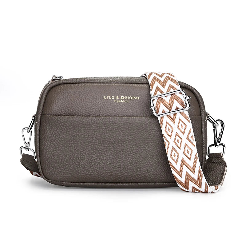 Gray crossbody bag with a patterned strap on a white background