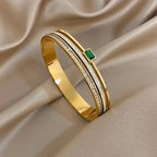 Gold bracelet with a green gemstone on a beige fabric background