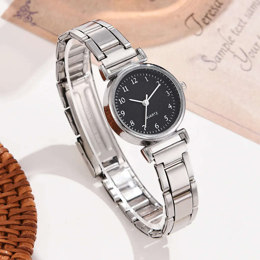 Silver watch with black dial on a white surface