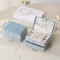 Blue jewelry box with jewelry inside, shown with dimensions on a light surface.