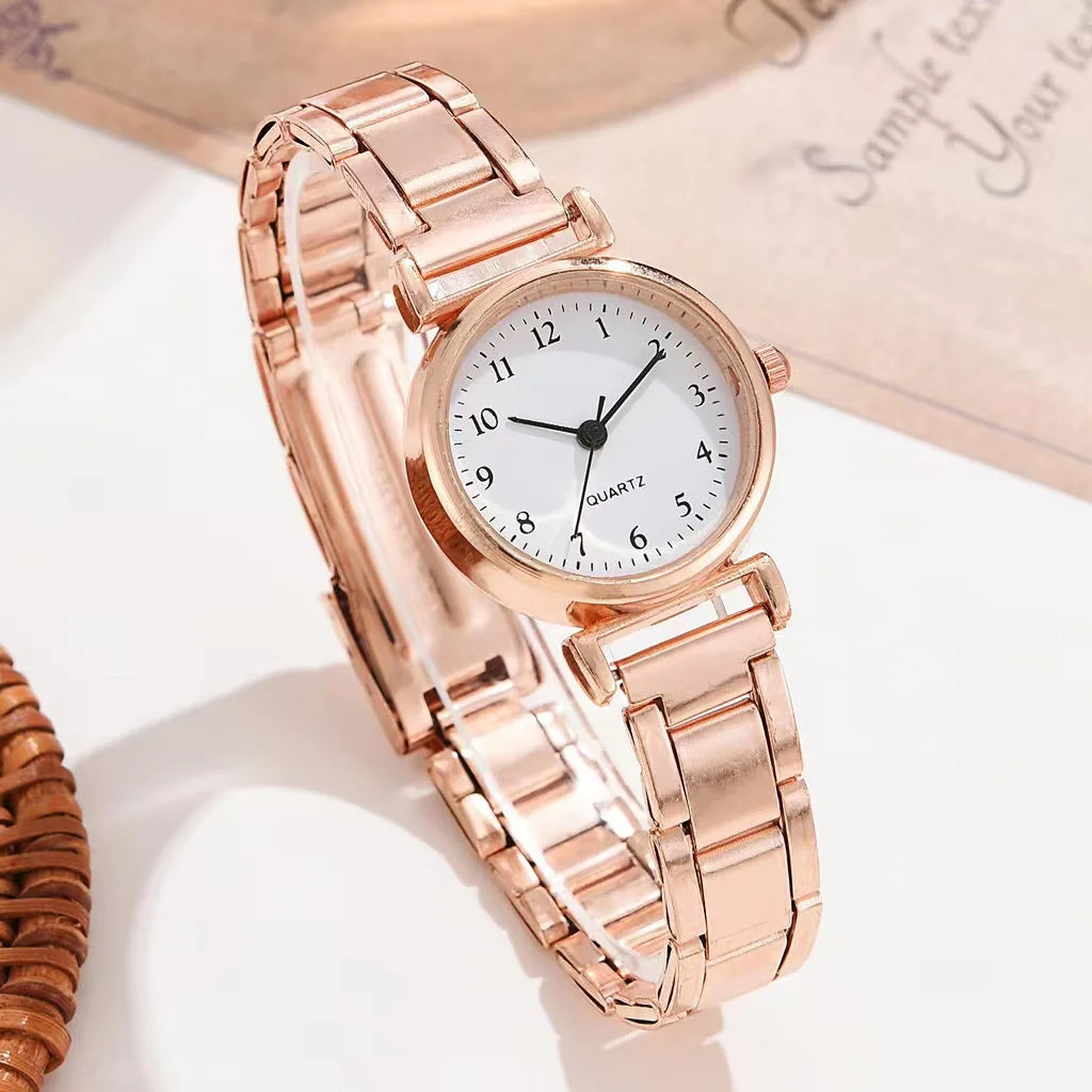 Rose gold watch with a white face on a light background