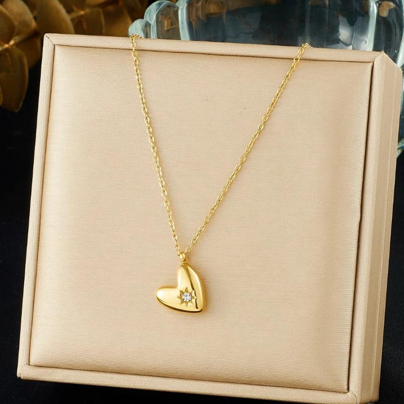 Gold heart-shaped necklace with a diamond on a beige jewelry box