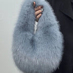 Blue faux fur scarf held by a person against a plain background