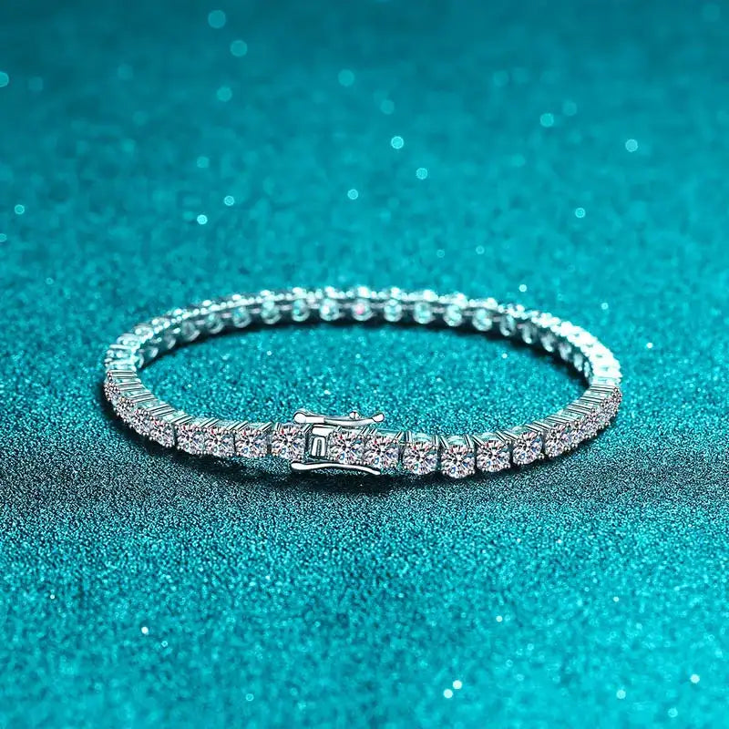 Silver bracelet with clear stones on a teal glittery background