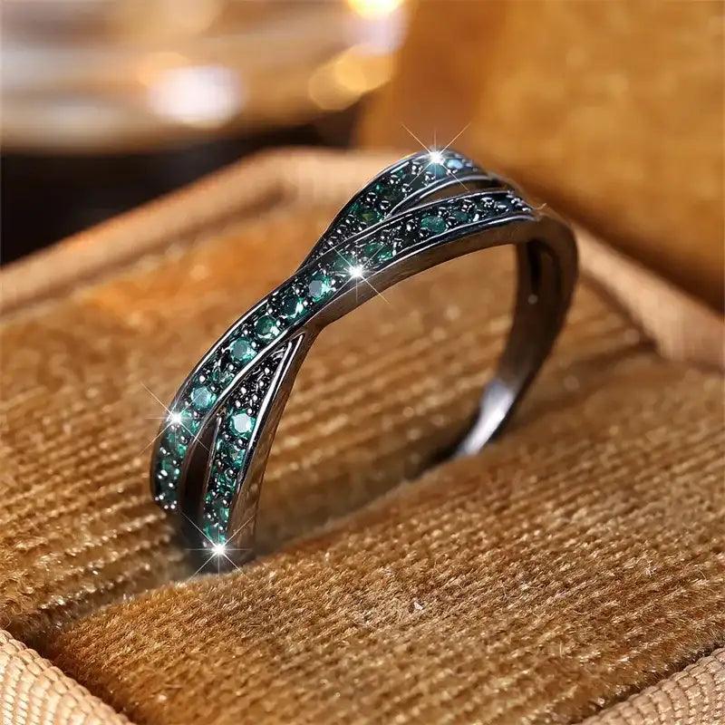Silver ring with green gemstones on a brown textured surface
