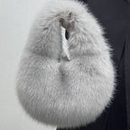 Gray fur stole held by a person against a light gray background