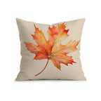 A square beige throw pillow featuring a large watercolor-style autumn maple leaf in orange, red, and yellow tones, shown on a clean white background.