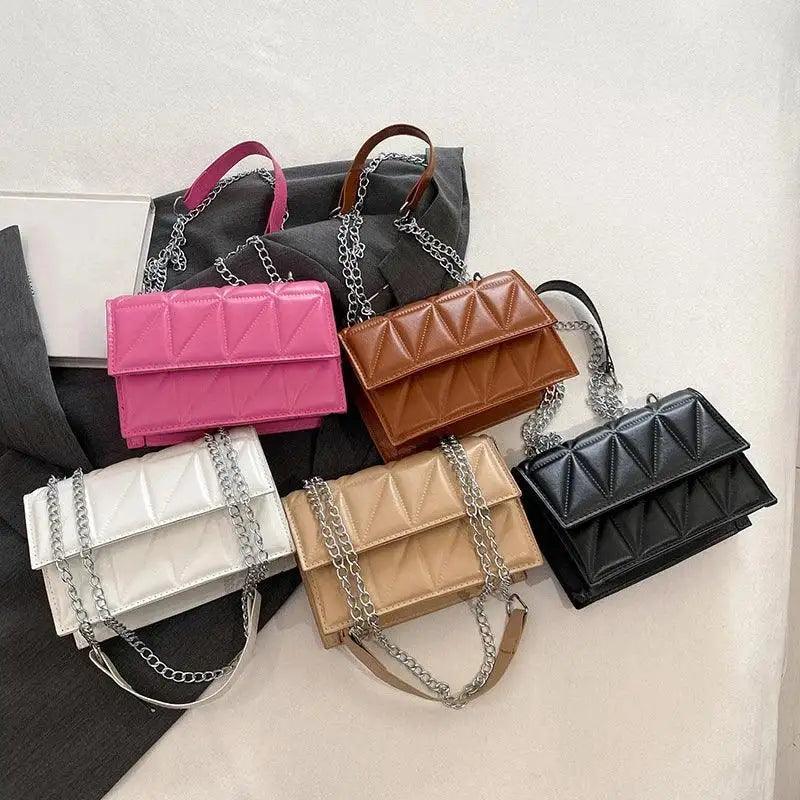 Collection of colorful handbags with chain straps on a light background