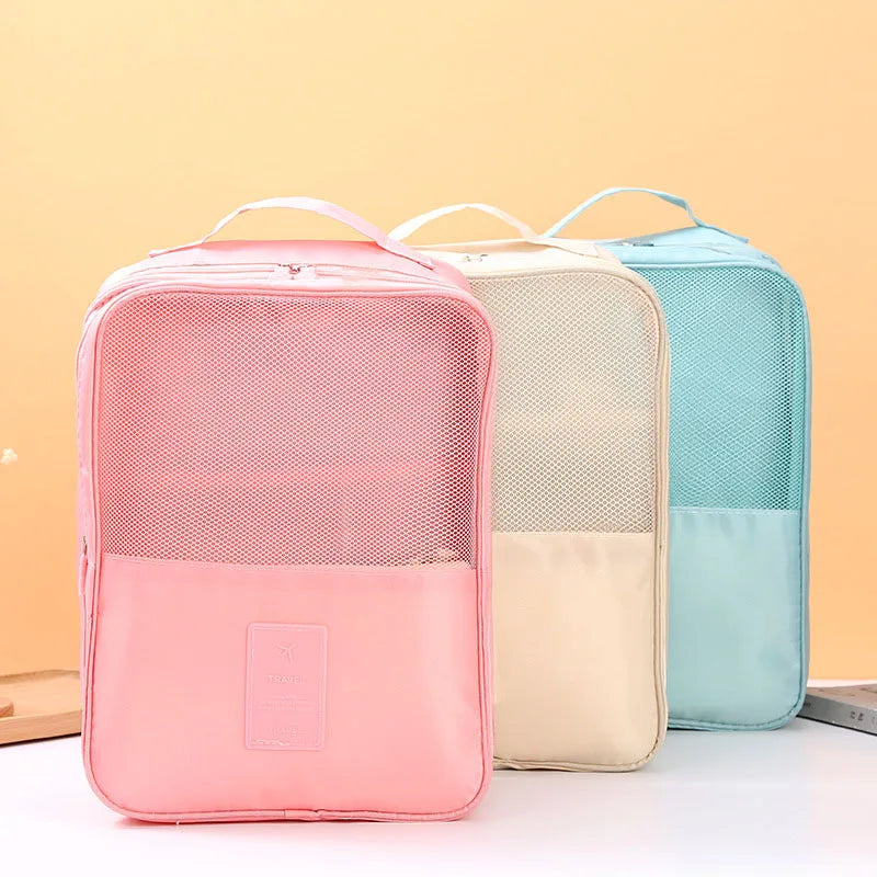 Three mesh packing cubes in pink, beige, and blue on a light background