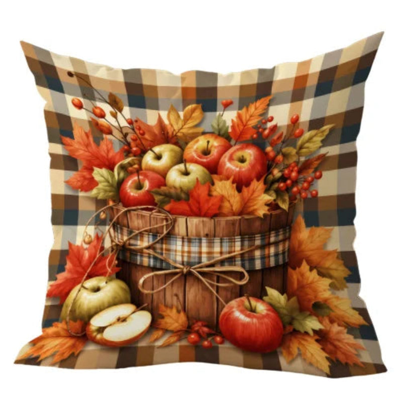 A square decorative throw pillow featuring a rustic autumn harvest print with red and green apples, orange and yellow leaves, berries, and a brown plaid patterned background, shown on a white background.