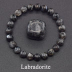 Labradorite stone with a bracelet made of similar stones on a dark background