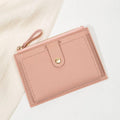 Pink wallet with a gold zipper on a light background