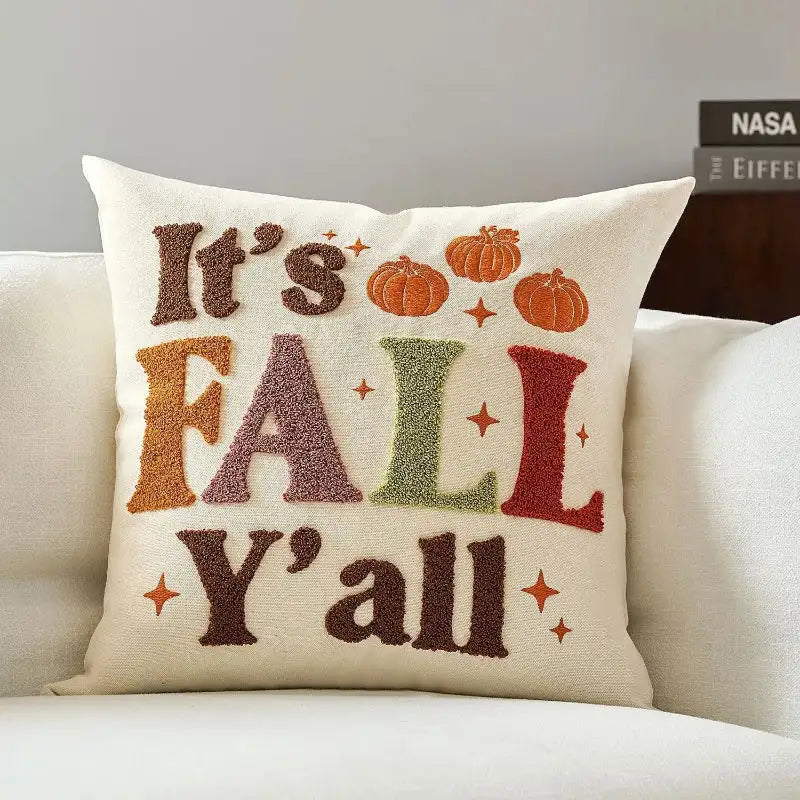 Decorative pillow with 'It's Fall Y'all' text and pumpkins on a couch.