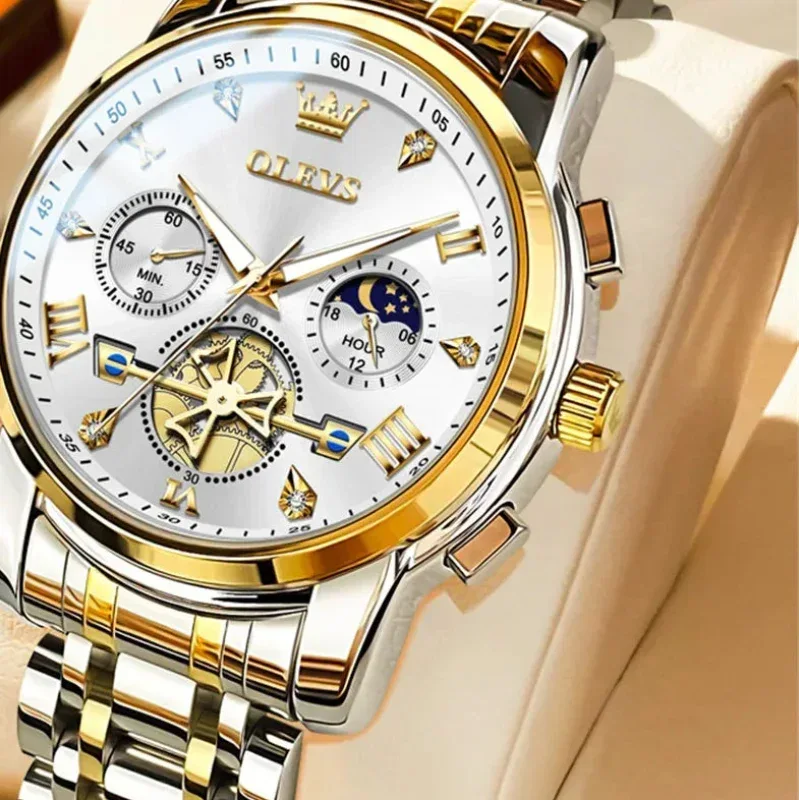 Gold and silver watch with detailed face on a beige background, featuring OLEVS branding.