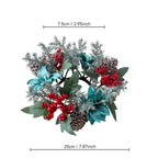 An artificial Christmas wreath with silver-green frosted branches, teal leaves, green leaves, red berry clusters, and pinecones, shown with dimension lines indicating 7.5 cm width at the top and 20 cm width at the bottom on a white background.