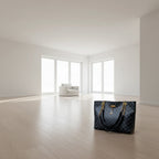Black patterned handbag with gold chains and a tag on a dark surface.