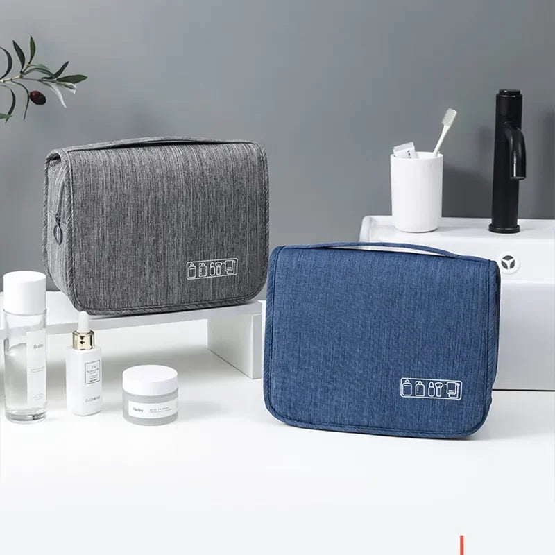 Two toiletry bags, one gray and one blue, on a white surface with skincare products.
