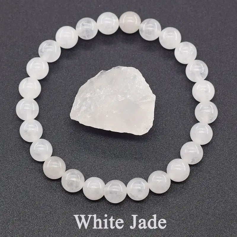 White jade bracelet and raw crystal on a dark gray background