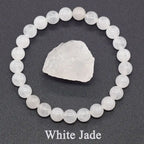 White jade bracelet and raw crystal on a dark gray background