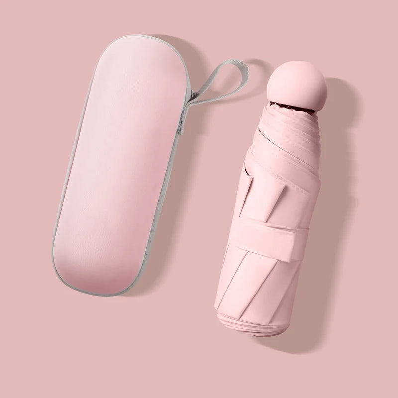 A compact pink folding umbrella and its matching oval carrying case, shown on a soft pink background.