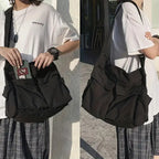 Person holding a black bag with a white shirt and plaid skirt outdoors.