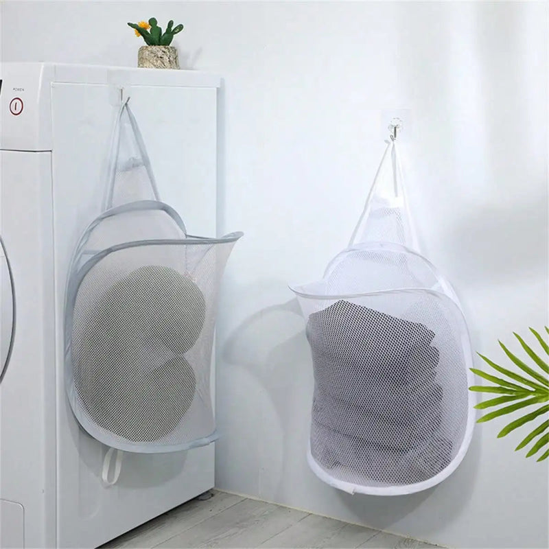 Mesh laundry bags hanging on a hook with clothes inside, next to a washing machine.