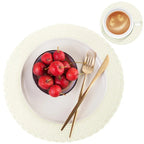 Bowl of red apples on a white plate with gold fork and knife, and a cup of coffee on a white background