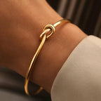 Gold bracelet on a wrist with a neutral background