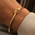 Gold bracelet on a wrist with a neutral background