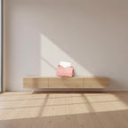 Pink pouch with 'SUNSHINE' text on a wooden surface with a magazine and decorative item in the background.