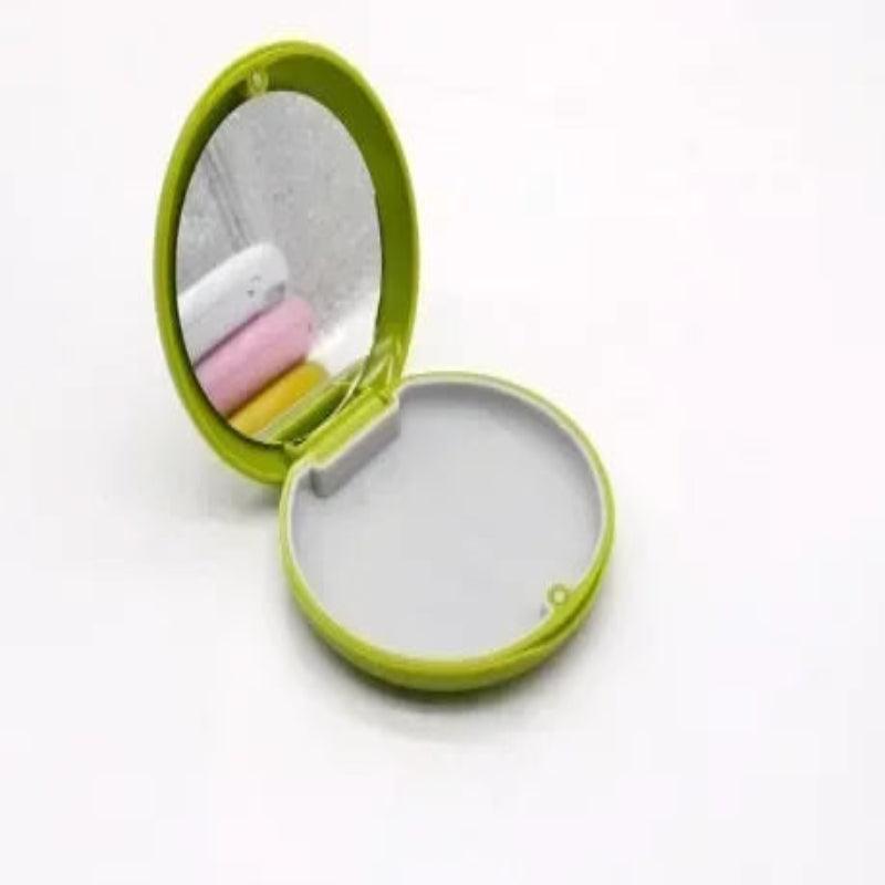 Green compact mirror with pink and yellow items on a white background